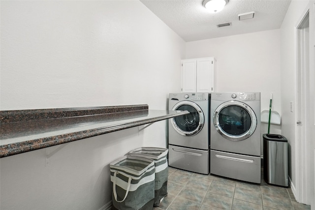 washroom with light tile patterned floors, visible vents, cabinet space, separate washer and dryer, and a textured ceiling