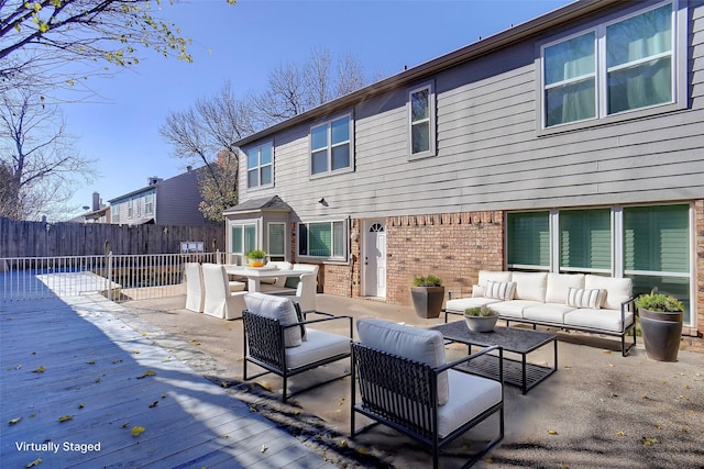 back of property with an outdoor hangout area, brick siding, a deck, and fence