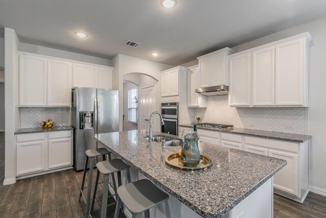 kitchen with sink, stainless steel appliances, an island with sink, pendant lighting, and white cabinets