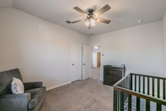 bedroom featuring a nursery area, light colored carpet, and ceiling fan