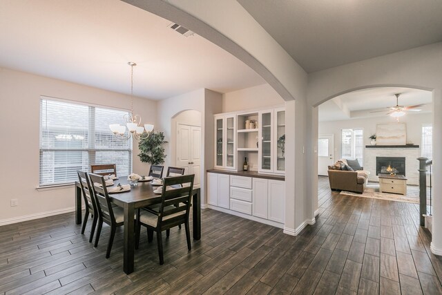 living room with a raised ceiling, a stone fireplace, ceiling fan, and sink