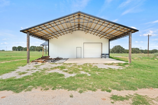 view of outdoor structure featuring a rural view, a garage, and a yard