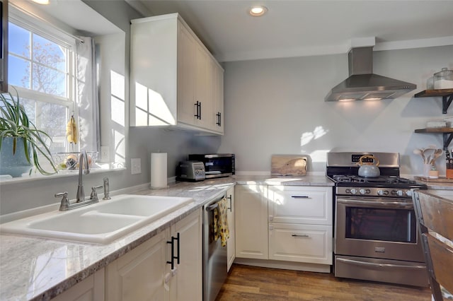 kitchen featuring light stone countertops, sink, stainless steel appliances, wall chimney range hood, and white cabinets