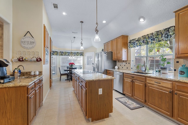 kitchen featuring appliances with stainless steel finishes, a center island, decorative light fixtures, and sink