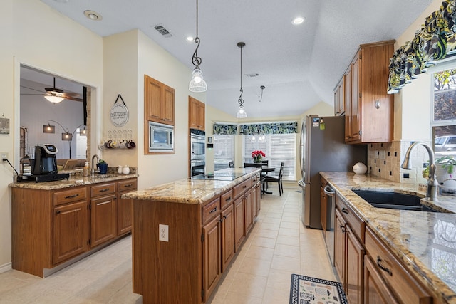 kitchen with sink, hanging light fixtures, ceiling fan, a kitchen island, and stainless steel appliances