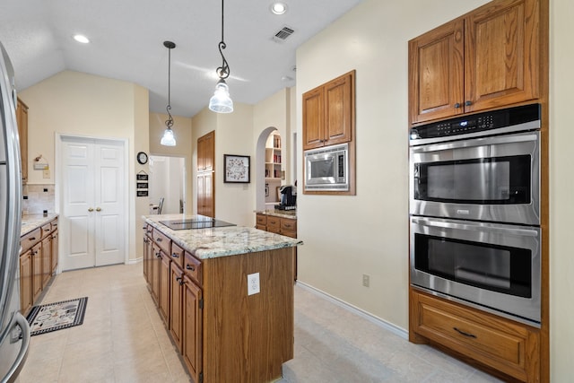 kitchen with hanging light fixtures, stainless steel appliances, light stone counters, vaulted ceiling, and a kitchen island