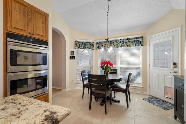 dining space featuring a textured ceiling, light tile patterned floors, lofted ceiling, and an inviting chandelier