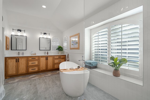 bathroom with a washtub, vanity, and vaulted ceiling