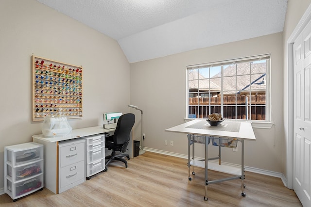 office space featuring light hardwood / wood-style floors, lofted ceiling, and a textured ceiling