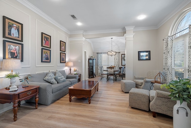 living room with decorative columns, light hardwood / wood-style floors, a notable chandelier, and ornamental molding