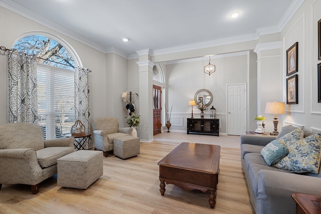 living room featuring light hardwood / wood-style floors, ornamental molding, and decorative columns