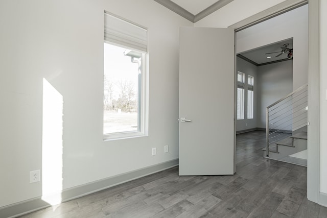 empty room with ceiling fan, crown molding, and wood-type flooring