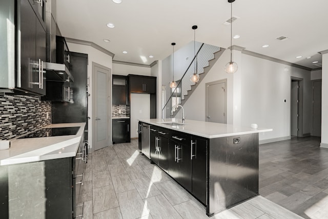 kitchen with stainless steel dishwasher, pendant lighting, a center island with sink, backsplash, and sink