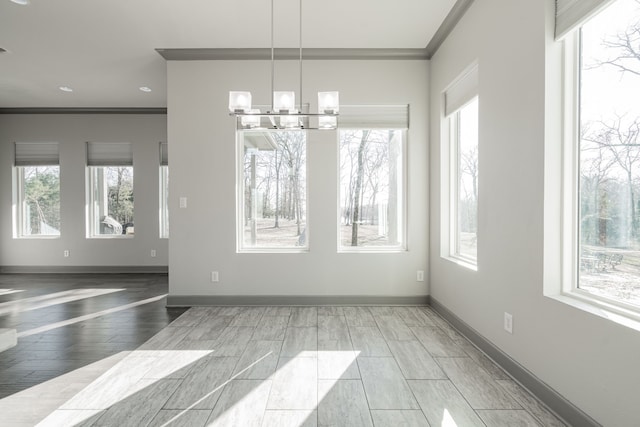 unfurnished dining area with ornamental molding, plenty of natural light, and a notable chandelier