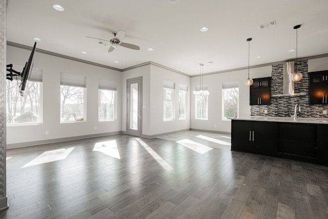 living room with ceiling fan with notable chandelier, ornamental molding, wood-type flooring, and sink