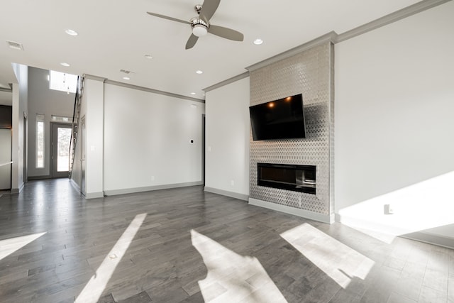 unfurnished living room featuring a fireplace, dark wood-type flooring, ceiling fan, and ornamental molding