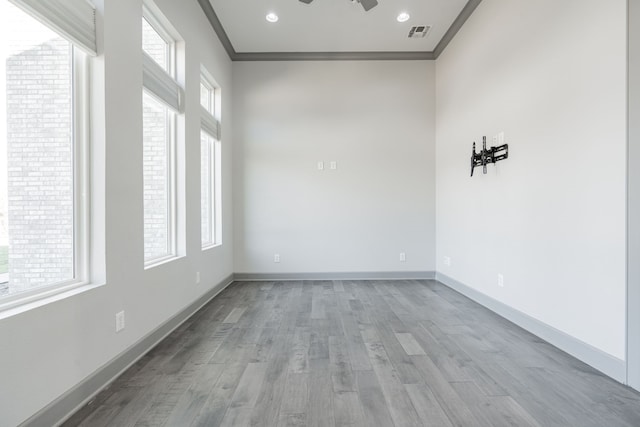 spare room with ornamental molding, ceiling fan, light wood-type flooring, and a wealth of natural light