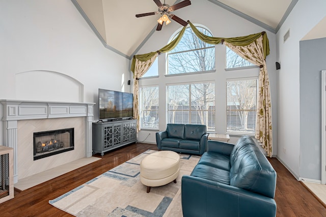 living room featuring a tile fireplace, ceiling fan, high vaulted ceiling, and dark wood-type flooring