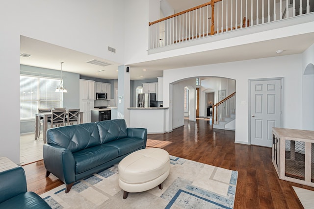 living room with a high ceiling, dark hardwood / wood-style floors, and a notable chandelier