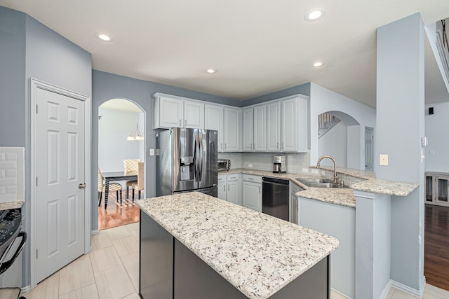 kitchen with sink, light stone countertops, appliances with stainless steel finishes, tasteful backsplash, and kitchen peninsula