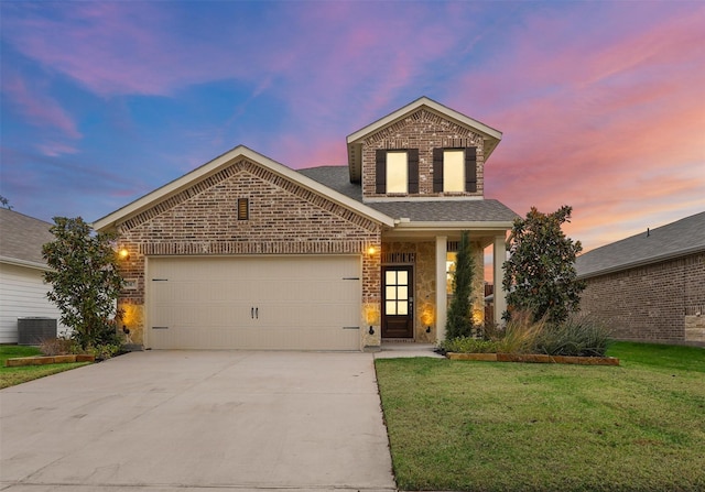 view of property featuring a garage, a yard, and central AC unit