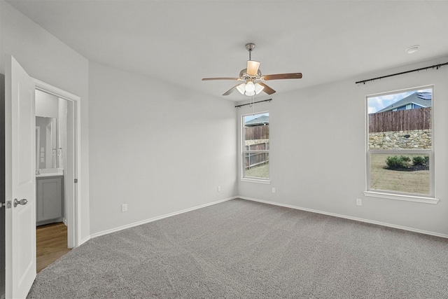 carpeted spare room featuring ceiling fan and a wealth of natural light