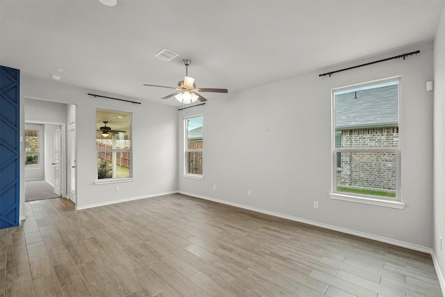 empty room with a wealth of natural light, light hardwood / wood-style flooring, and ceiling fan