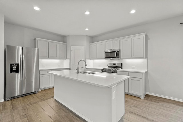 kitchen featuring decorative backsplash, stainless steel appliances, sink, a center island with sink, and white cabinets