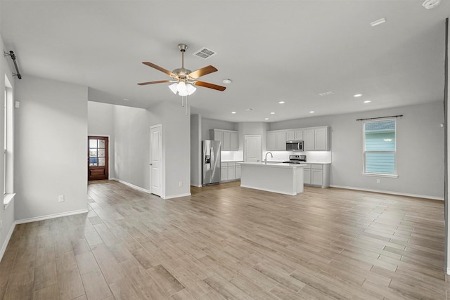 unfurnished living room featuring light hardwood / wood-style flooring, ceiling fan, and sink