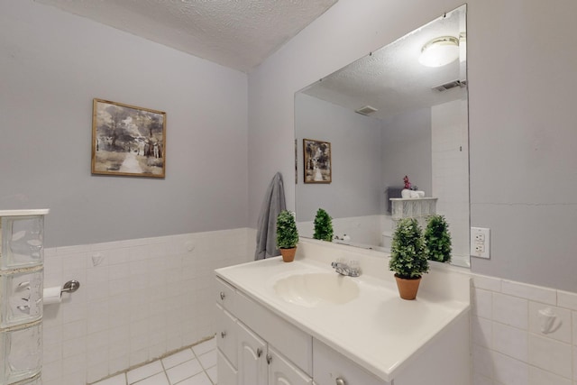 bathroom featuring vanity, tile patterned flooring, tile walls, and a textured ceiling