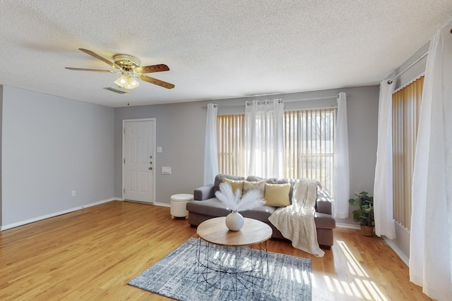 living room featuring ceiling fan, a textured ceiling, and light hardwood / wood-style floors