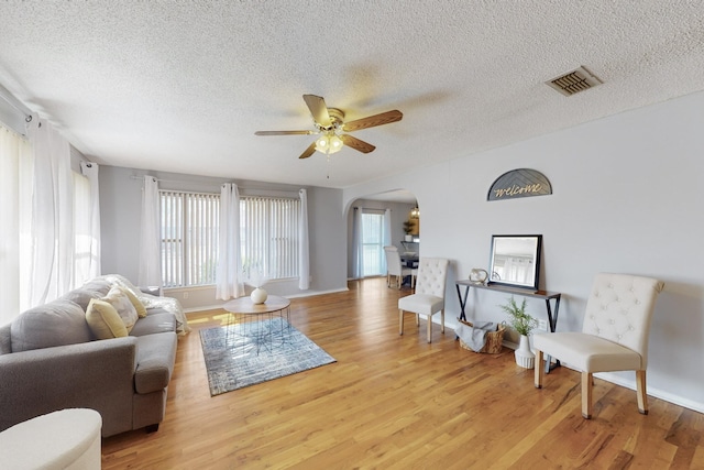 living room featuring ceiling fan, a textured ceiling, and light hardwood / wood-style flooring