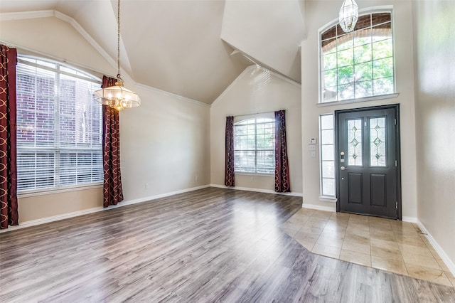 foyer entrance featuring vaulted ceiling, an inviting chandelier, and light hardwood / wood-style flooring