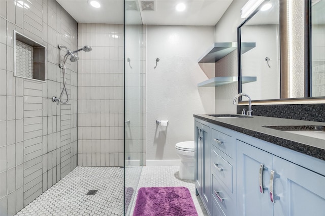 bathroom with tile patterned flooring, vanity, toilet, and tiled shower