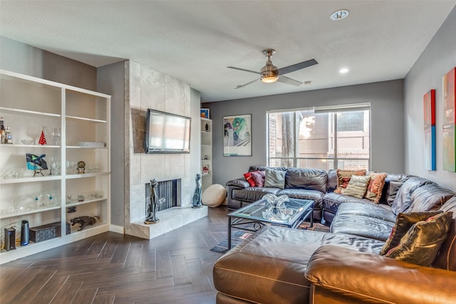 living room with ceiling fan, a large fireplace, and dark parquet flooring