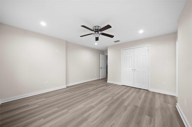 unfurnished bedroom featuring ceiling fan, light hardwood / wood-style floors, and a closet