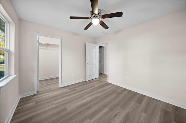 unfurnished bedroom with a closet, light hardwood / wood-style flooring, a spacious closet, and ceiling fan