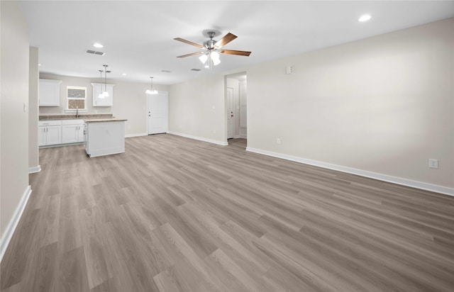 unfurnished living room with ceiling fan, light hardwood / wood-style flooring, and sink