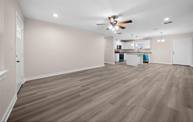 unfurnished living room featuring sink, wood-type flooring, and ceiling fan with notable chandelier