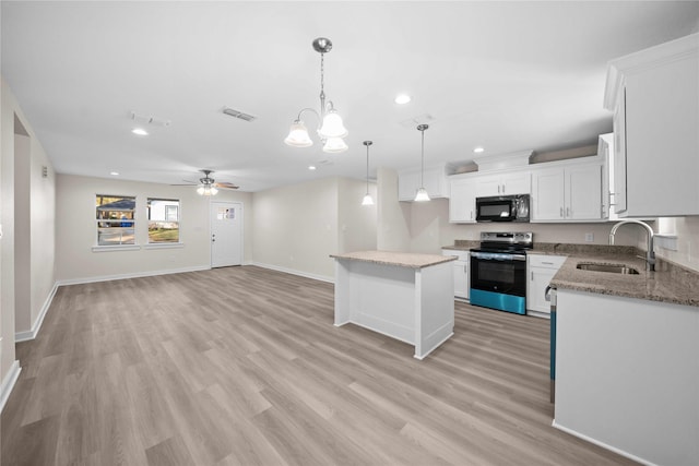 kitchen with stainless steel range with electric stovetop, a center island, ceiling fan with notable chandelier, sink, and white cabinetry