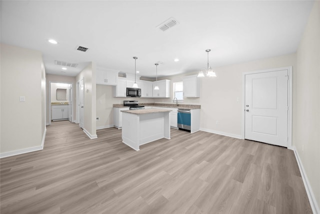 kitchen featuring appliances with stainless steel finishes, light wood-type flooring, pendant lighting, white cabinets, and a center island