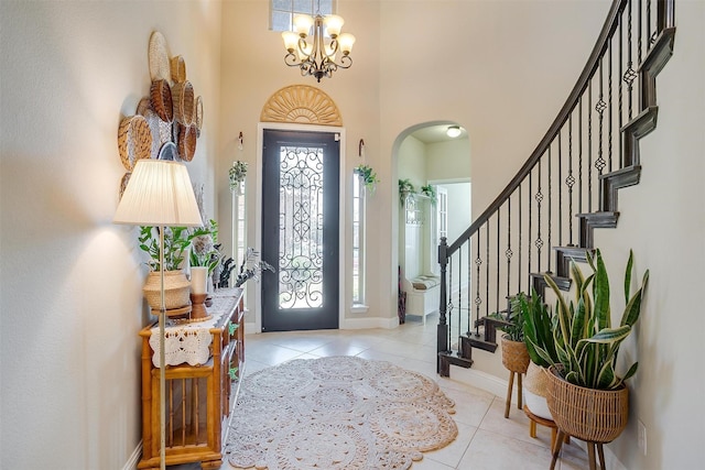 entryway featuring a towering ceiling, light tile patterned flooring, and a notable chandelier