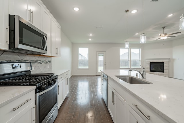 kitchen featuring sink, stainless steel appliances, tasteful backsplash, white cabinets, and decorative light fixtures