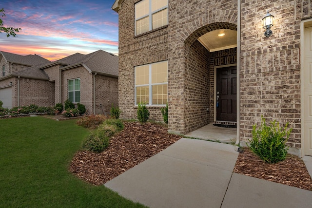 exterior entry at dusk featuring a lawn