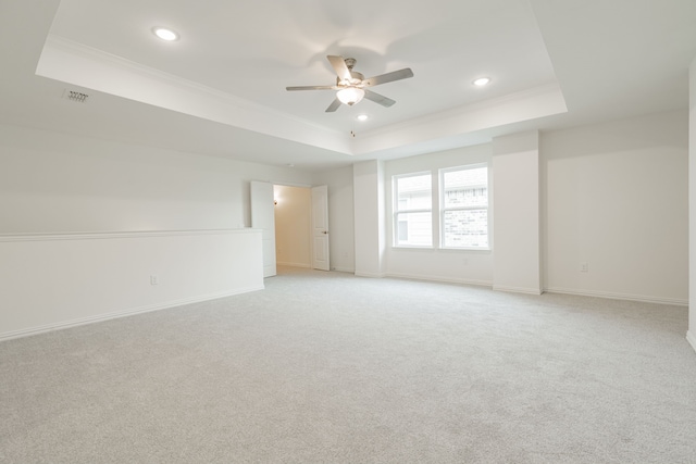 carpeted spare room featuring a tray ceiling, ceiling fan, and crown molding