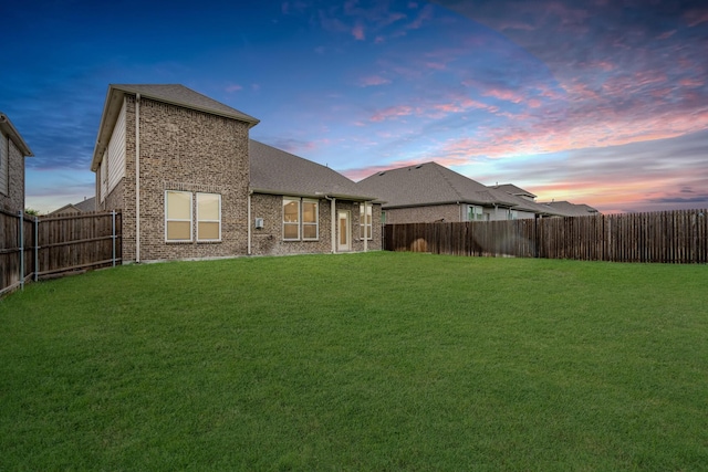 back house at dusk with a lawn