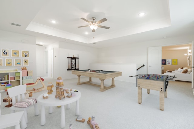 playroom with ceiling fan, billiards, light colored carpet, a tray ceiling, and ornamental molding