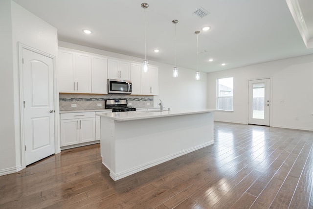 kitchen with stainless steel appliances, a kitchen island with sink, sink, decorative light fixtures, and white cabinetry