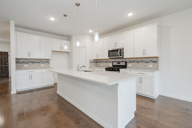 kitchen with sink, stainless steel appliances, an island with sink, decorative light fixtures, and white cabinets