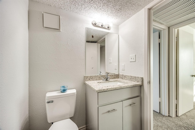 bathroom featuring vanity, toilet, and a textured ceiling